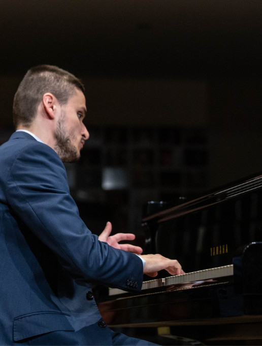 Portrait du pianiste aveugle Iulian Ionut Abagiu jouant sur un piano Yamaha lors d’un concert.